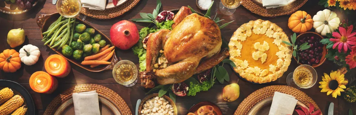 Overhead view of a complete holiday dinner spread with a golden roasted turkey, pumpkin pie, and side dishes